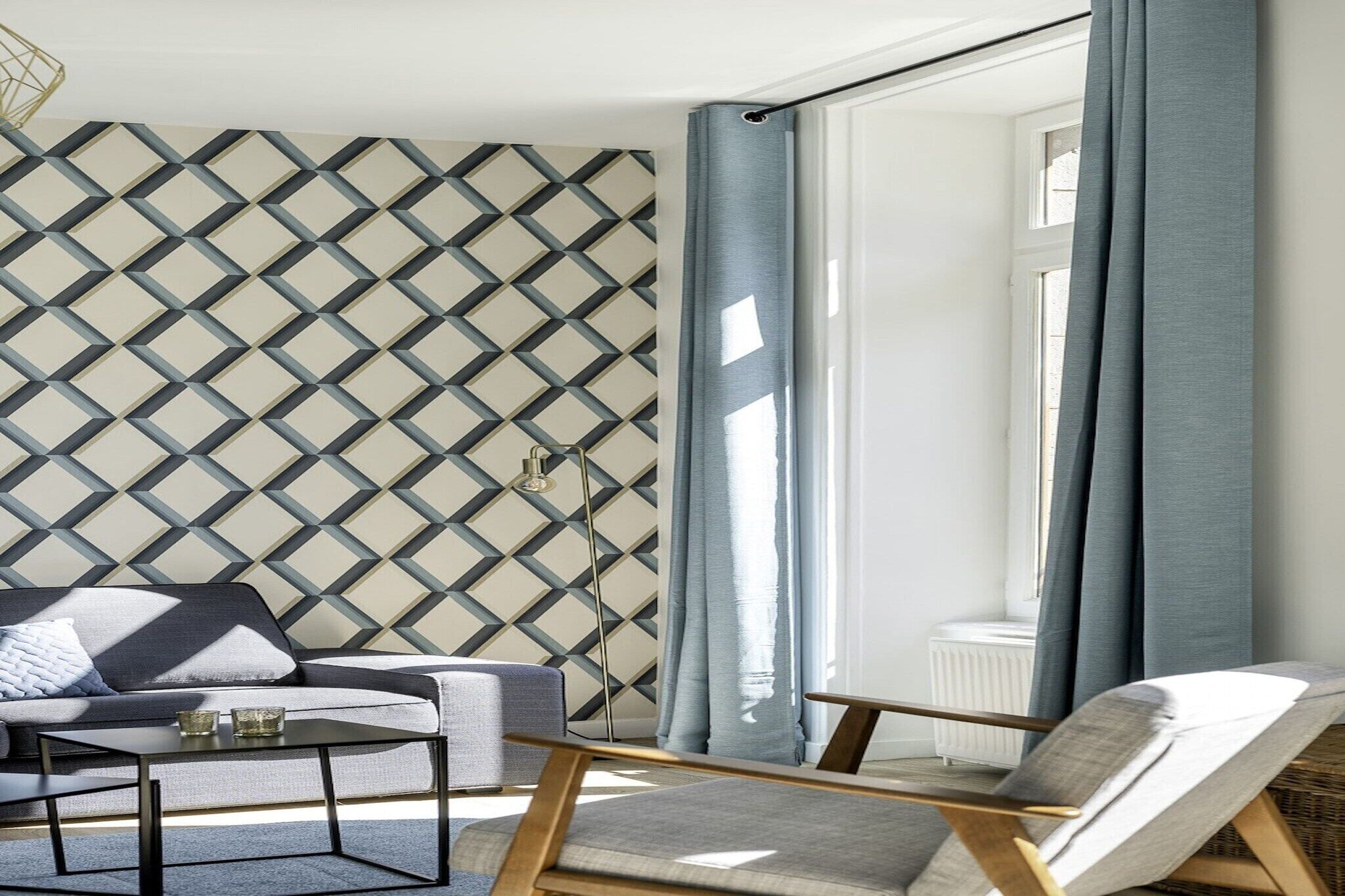 Un salon moderne avec un mur orné d’un motif géométrique, un canapé, une table basse et un fauteuil.