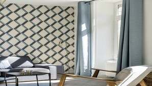 Un soggiorno moderno con una parete a motivi geometrici, un divano, un tavolino da caffè e una poltrona.