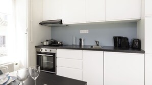 Una cucina moderna con mobili bianchi, un piano di lavoro nero, un forno, una stufa e una macchina da caffè.