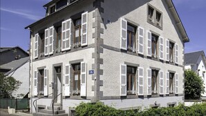 Un edificio a due piani con pareti esterne bianche, numerose finestre con persiane e una scala visibile che conduce all'ingresso.