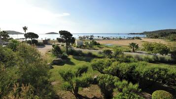 A coastal area with a parking lot, greenery, and a view of the sea.
