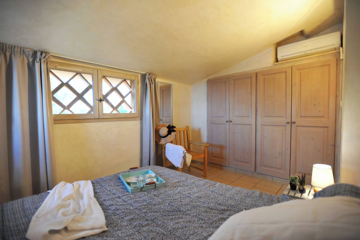 A bedroom with a bed, a chair, a window, and a wardrobe.