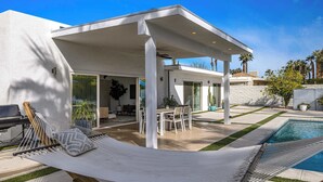 Une maison moderne dotée d’une piscine, d’un espace salon extérieur et d’un hamac.