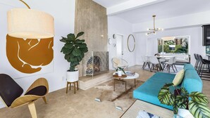 Un salon moderne avec un canapé, une table basse et un coin repas comprenant une table et des chaises blanches.