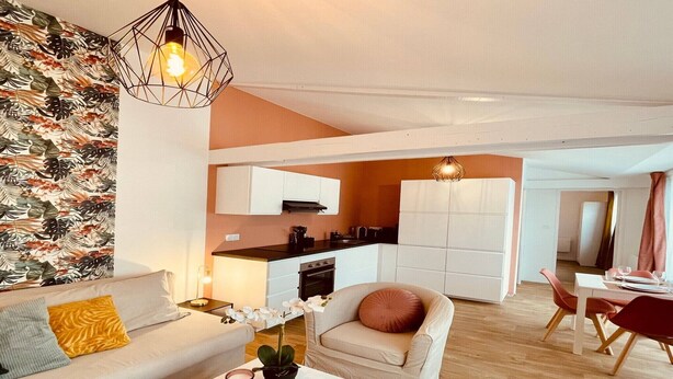 Una sala de estar moderna con un sofá, una mesa baja con una planta y un comedor con una mesa y sillas.