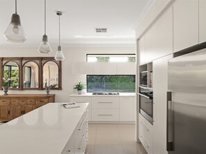 A modern kitchen with white cabinetry, a stainless steel refrigerator, and pendant lighting. - Ile-de-Re: Generous Garden Home by the Beach (Dunsborough)