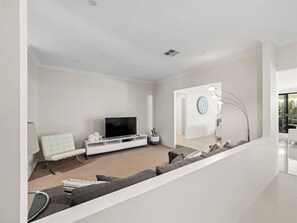 A modern living room with a flat-screen TV, a white sofa, a light-colored armchair, and a white console table. - Ile-de-Re: Generous Garden Home by the Beach (Dunsborough)