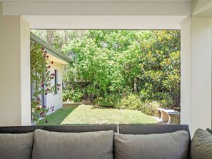 A patio with a wicker sofa, a small garden, and a white wall with climbing plants. - Ile-de-Re: Generous Garden Home by the Beach (Dunsborough)