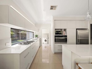 A modern kitchen with white cabinetry, a built-in oven, and a stainless steel refrigerator. - Ile-de-Re: Generous Garden Home by the Beach (Dunsborough)