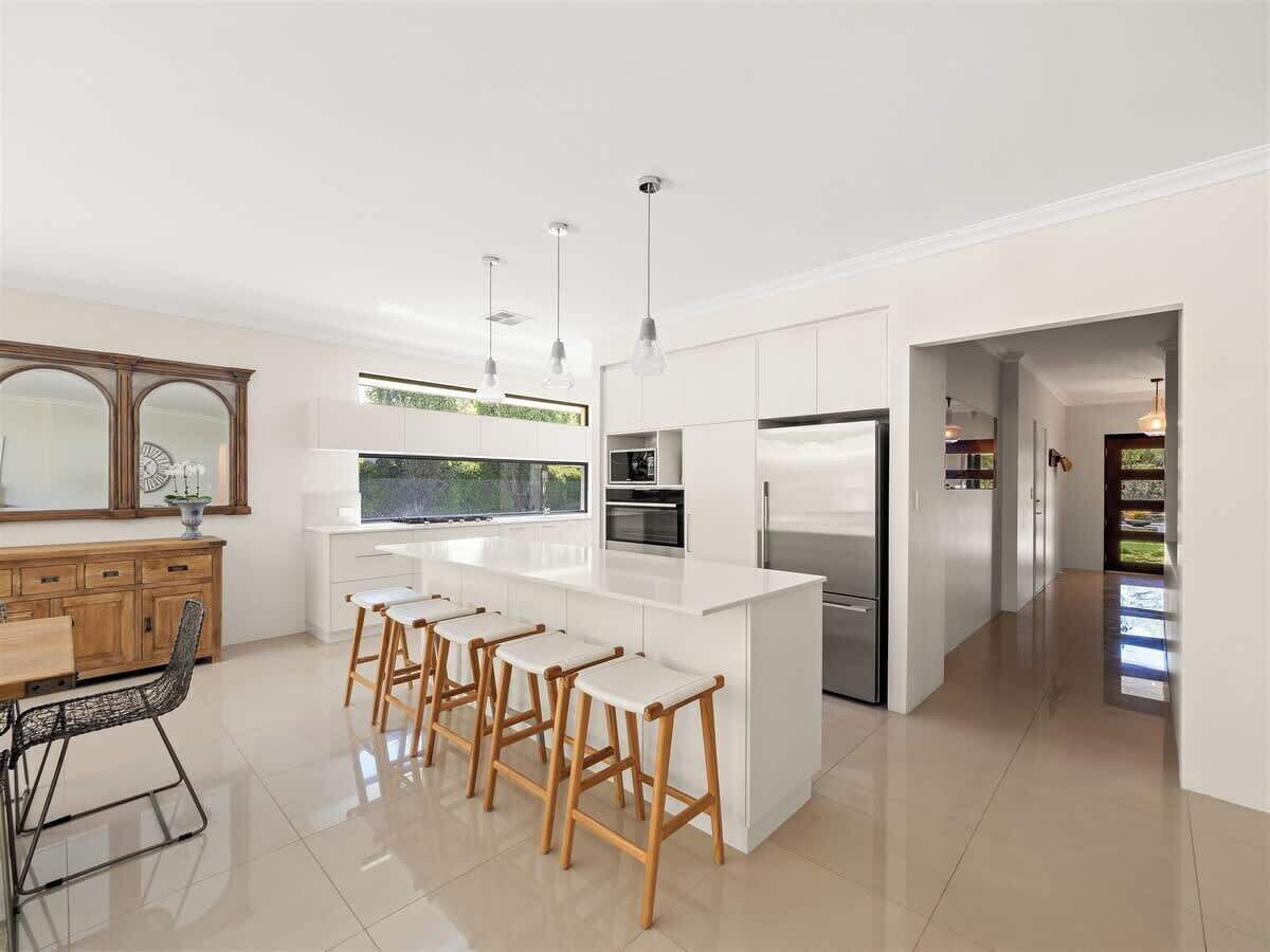 A modern kitchen with a central island, bar stools, and a dining area with a table and chairs.