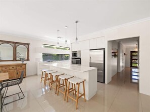 A modern kitchen with a central island, bar stools, and a dining area with a table and chairs. - Ile-de-Re: Generous Garden Home by the Beach (Dunsborough)
