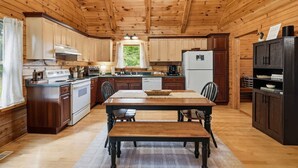 A wooden cabin interior with a kitchen, dining table, and chairs. - Private Woodland Retreat w/ Pond, Fireplace & (Watervliet)