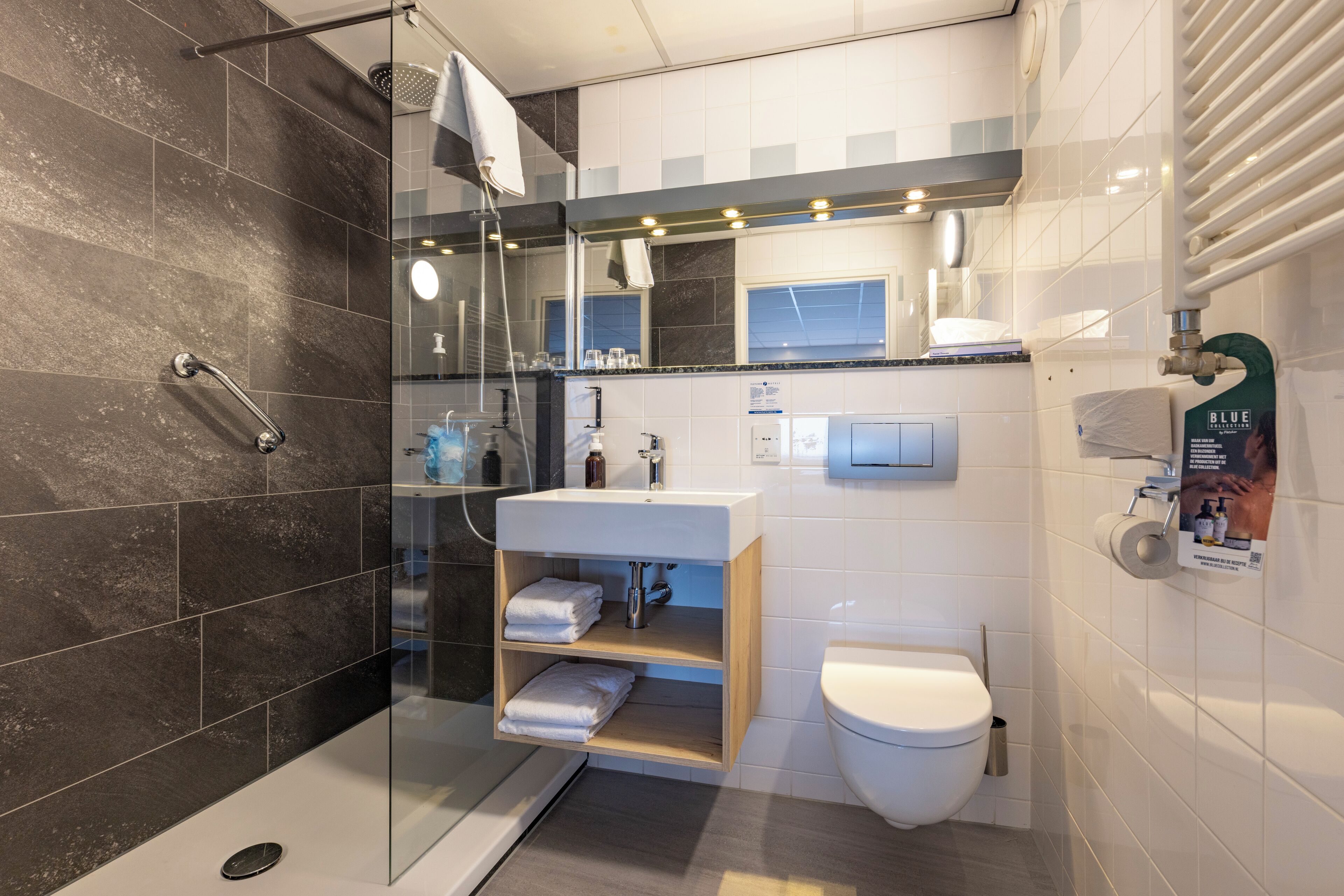 A modern bathroom with a glass shower enclosure, a white sink with a wooden vanity, and a toilet.