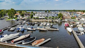A marina with various boats docked, surrounded by residential buildings and a view of the water.