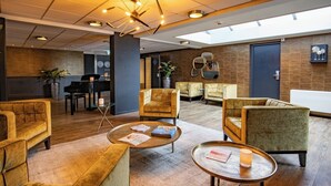 A modern lobby with a piano, comfortable seating, and a large window. - Stay Steps from the Marina with Nature Trails and Locally Inspired Dining (Loosdrecht)