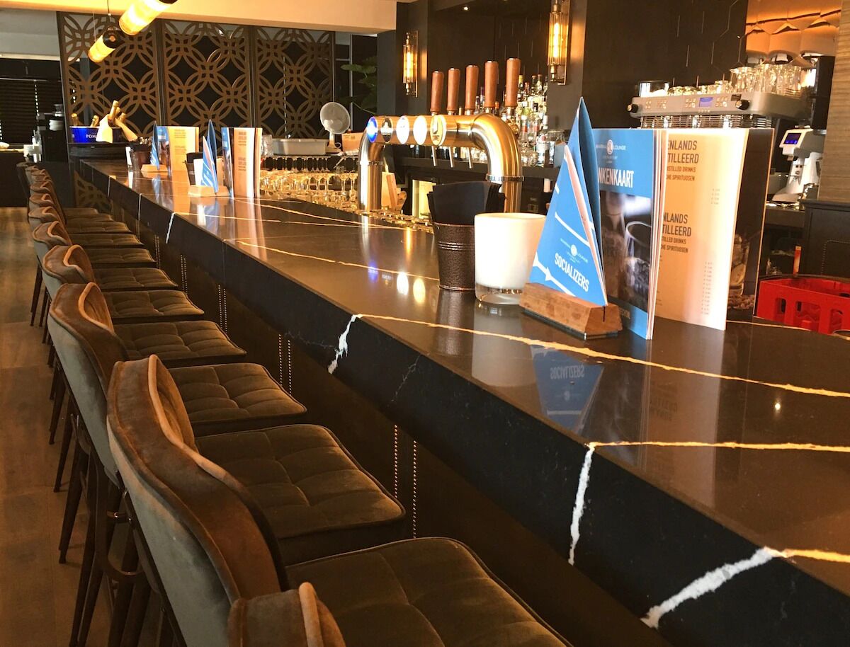 Un'area bar con un lungo bancone, diverse spine di birra e sgabelli da bar.
