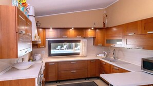 Een compacte keuken met houten kastjes, een ingebouwde magnetron, een groot raam met uitzicht en een klein eethoekje.