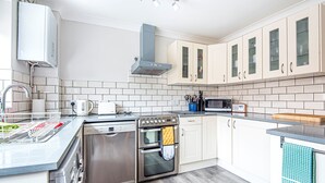 A modern kitchen with stainless steel appliances, white cabinetry, and a tiled backsplash. - Old Hunny Cottage - sleeps 5 guests  in 2 bedrooms (Old Hunstanton)