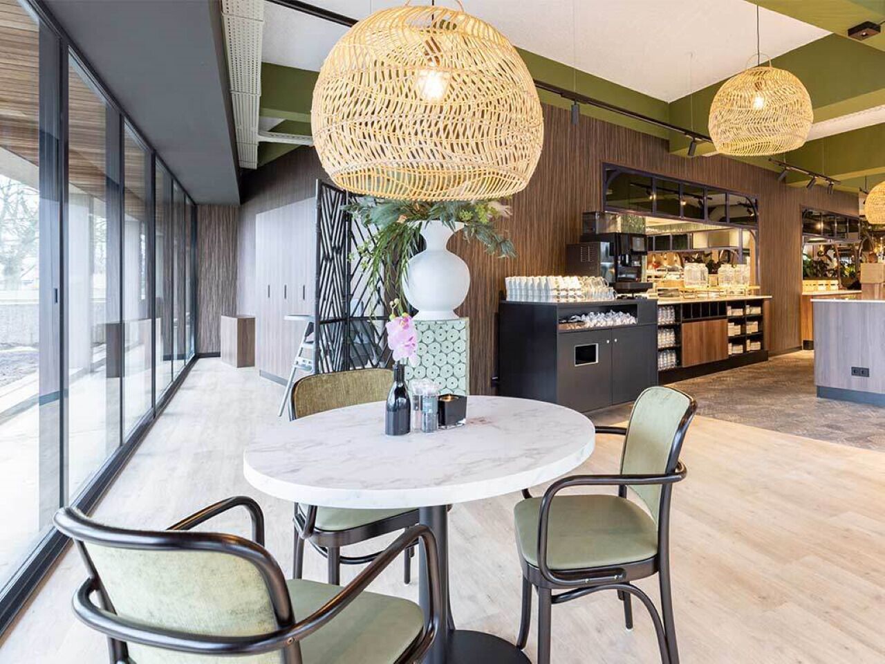 Un área de comedor moderna con una mesa redonda, sillas y un jarrón con flores.