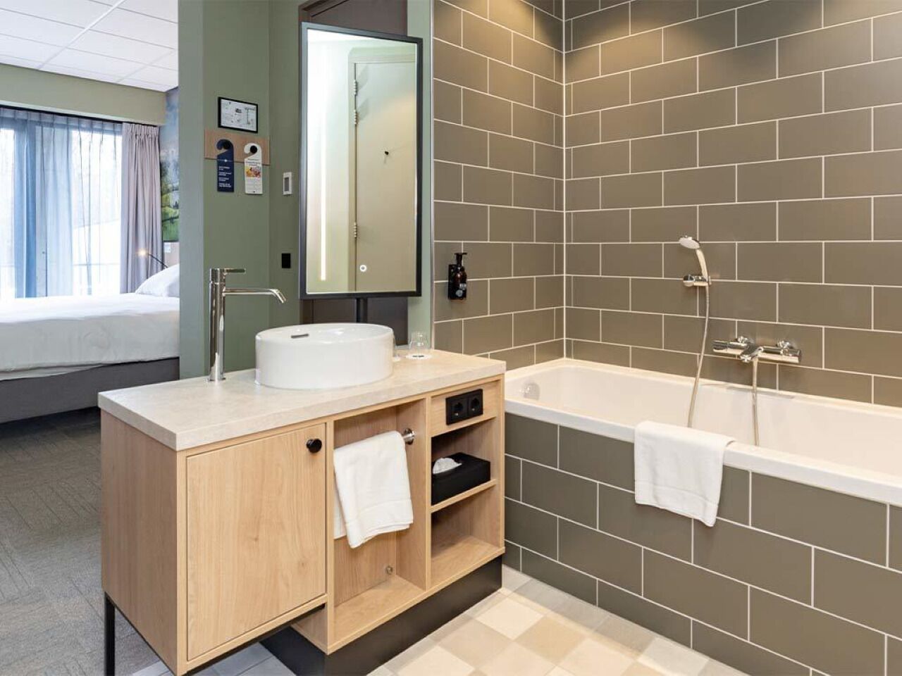 Een moderne badkamer met een beige wastafelmeubel, een grote spiegel, een badkuip en een douche.