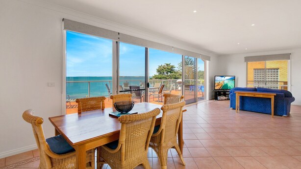 A spacious living area with a large sliding glass door leading to a balcony with a view of the sea. - Cowes Beachfront Penthouse (Cowes)