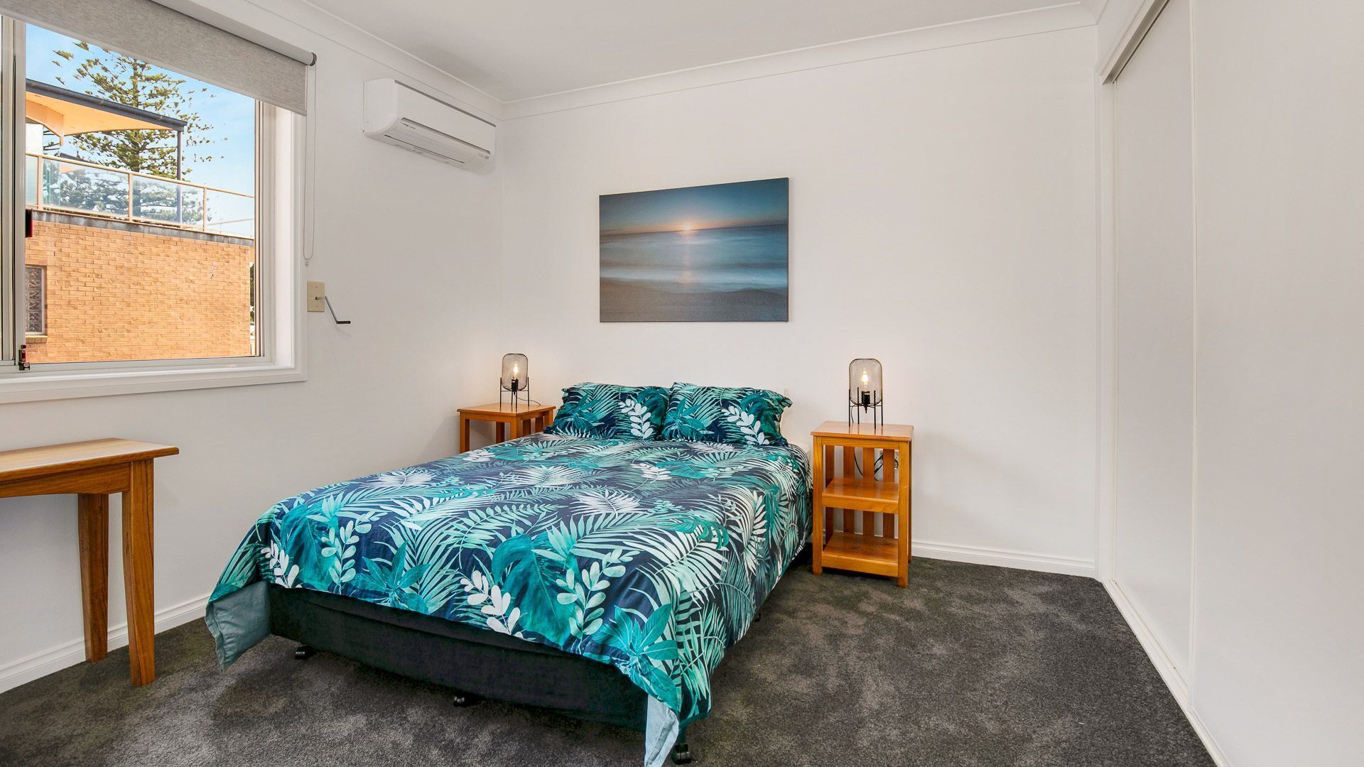 A bedroom with a bed, two nightstands, a window, and a painting on the wall.