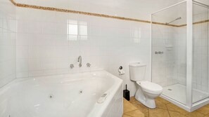 A bathroom with a bathtub, toilet, and glass-enclosed shower. - Cowes Beachfront Penthouse (Cowes)