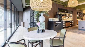 A modern dining area with a round table, chairs, and a vase with flowers.