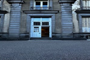 En byggnad med en framträdande entré, kännetecknad av en vit dörr och en liten balkong ovanför.