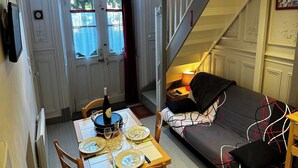 Ein Essbereich mit einem Tisch für zwei Personen, einer Couch und einer Treppe.