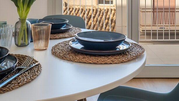 A dining table set with plates, cutlery, and a vase of flowers, with a view of the sea through a balcony railing. - Holiday Home 'Terrazza Marconi' with Sea View, Wi-Fi and Air Conditioning (Castellammare del Golfo)