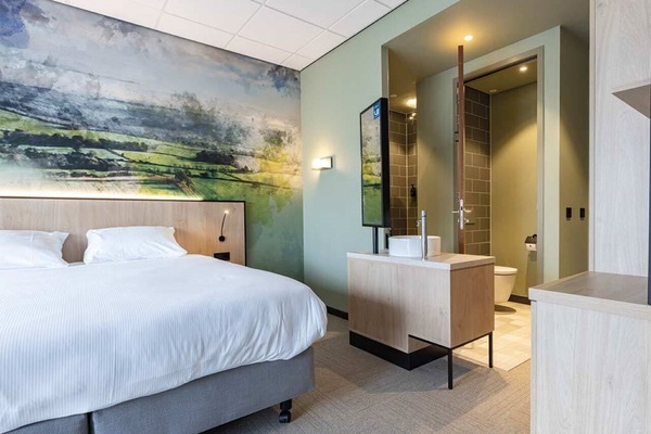 Drift off beneath statement wall art and crisp hotel linens.