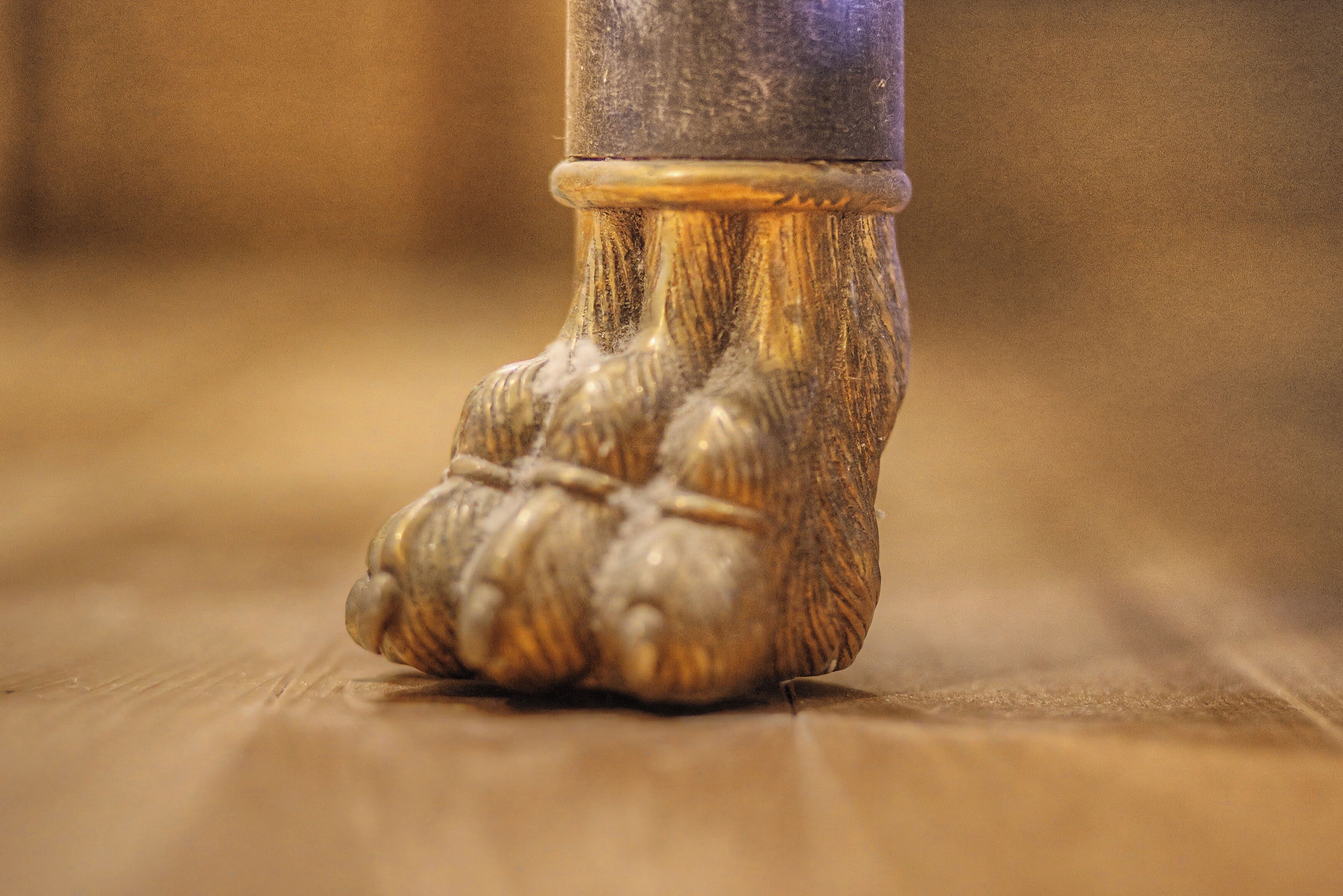 A close-up of a wooden floor with a carved legrest.