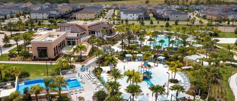 A residential area with a swimming pool, palm trees, and houses.
