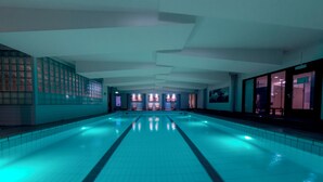 Une grande piscine intérieure dotée d’un sol carrelé et d’une forme longue et étroite.