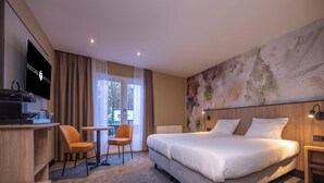 A hotel room with a bed, a desk with a TV, a chair, and a large window. - Relax and Play: Indoor Pool, Cycling Nearby, Game Room & Free Parking (Heelsum)