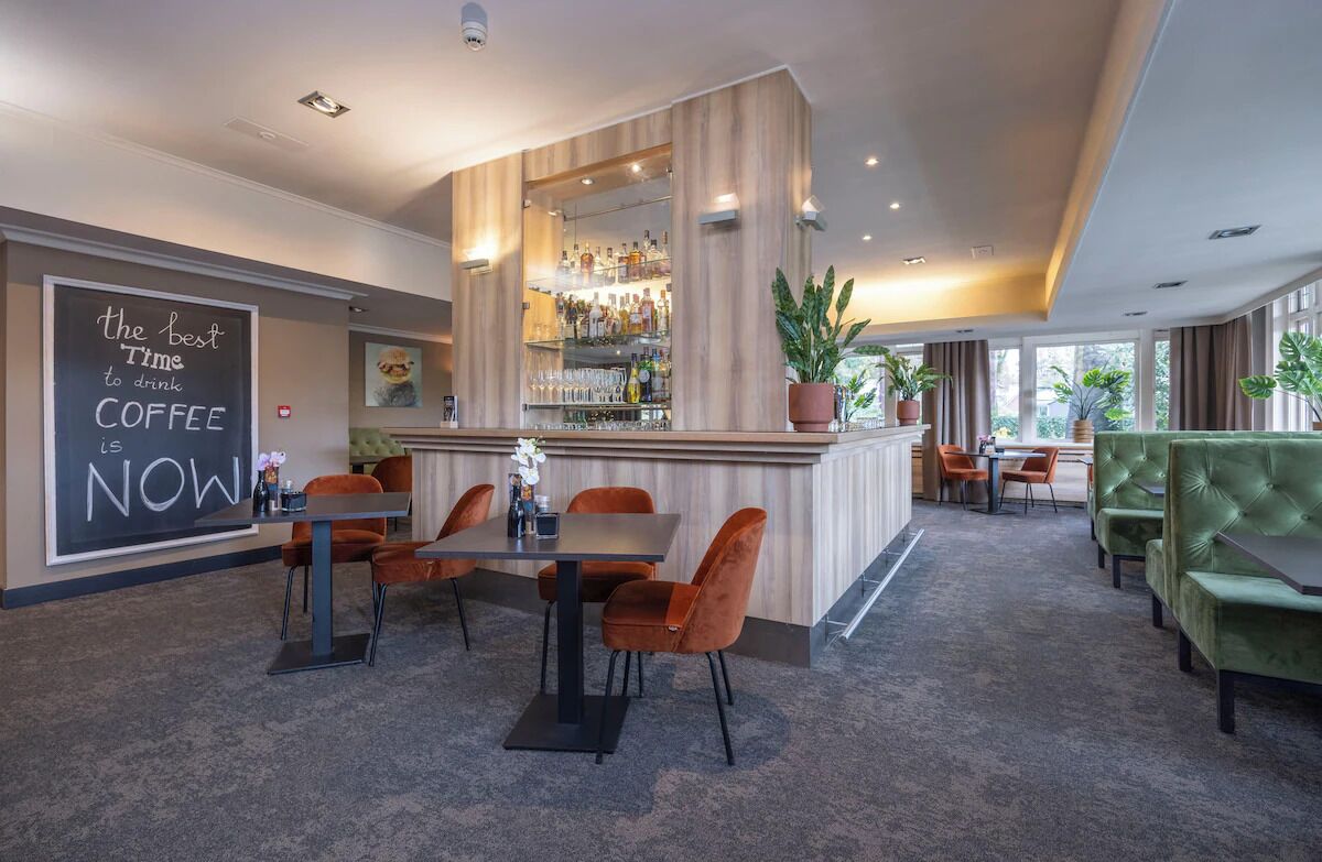 A modern bar area with a bar counter, seating, and a large potted plant.