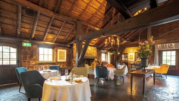 A rustic dining area with wooden beams, stone walls, and round tables set for dining. - Relax and Play: Indoor Pool, Cycling Nearby, Game Room & Free Parking (Heelsum)