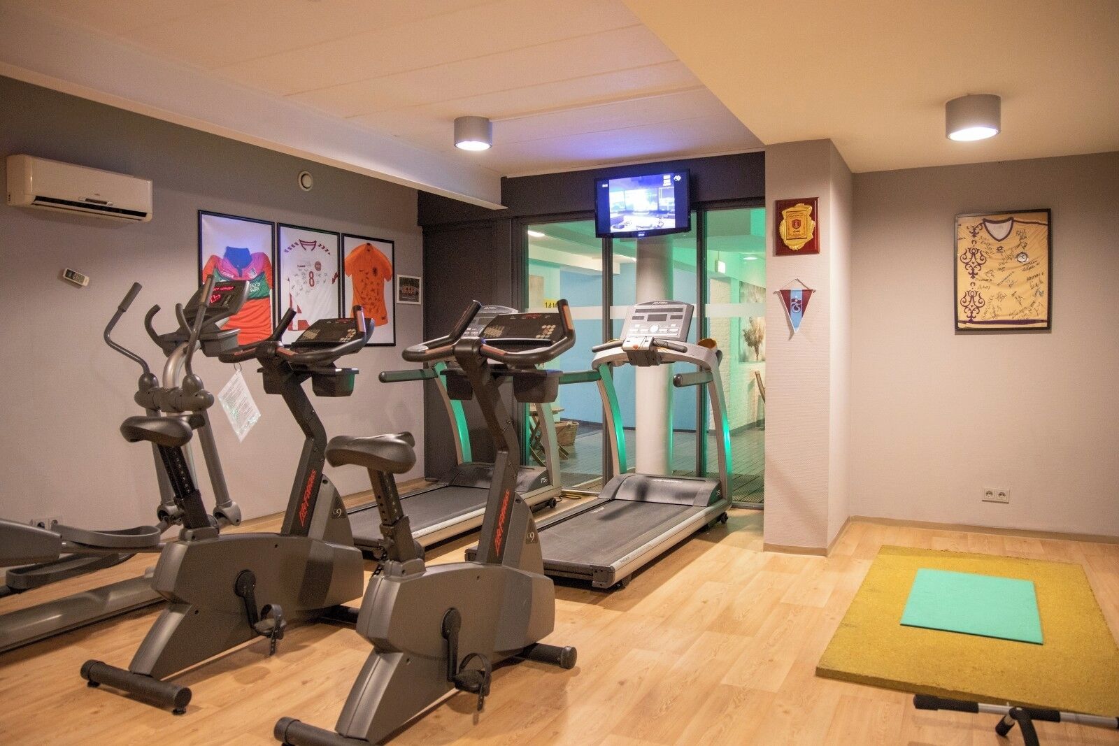 Une salle de sport équipée de tapis de course, de vélos d’appartement et d’un tapis de yoga.