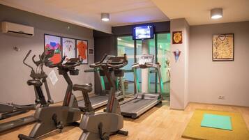 Une salle de sport équipée de tapis de course, de vélos d’appartement et d’un tapis de yoga.
