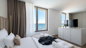 Une chambre d’hôtel avec un lit, une télévision et une vue sur la mer.