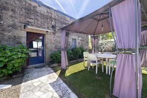 A covered patio with a table and chairs, a stone wall, and a door.