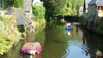 Un canal estrecho con barcos, casas a lo largo de las orillas y una embarcación llena de flores en primer plano.