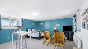 Ein Zimmer mit Bett, Fernseher, Tisch mit Stühlen und einem Fenster mit Vorhängen.