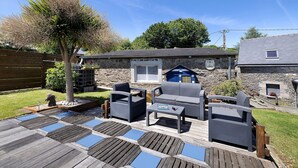 Eine Terrasse mit Gartenmöbeln, ein Steinhaus und klarer Himmel.