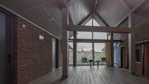 Een interieur met een hoge plafond, bakstenen muren en uitzicht door grote ramen.
