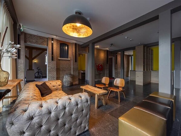 A modern lobby with a tufted sofa, wooden tables, and chairs.