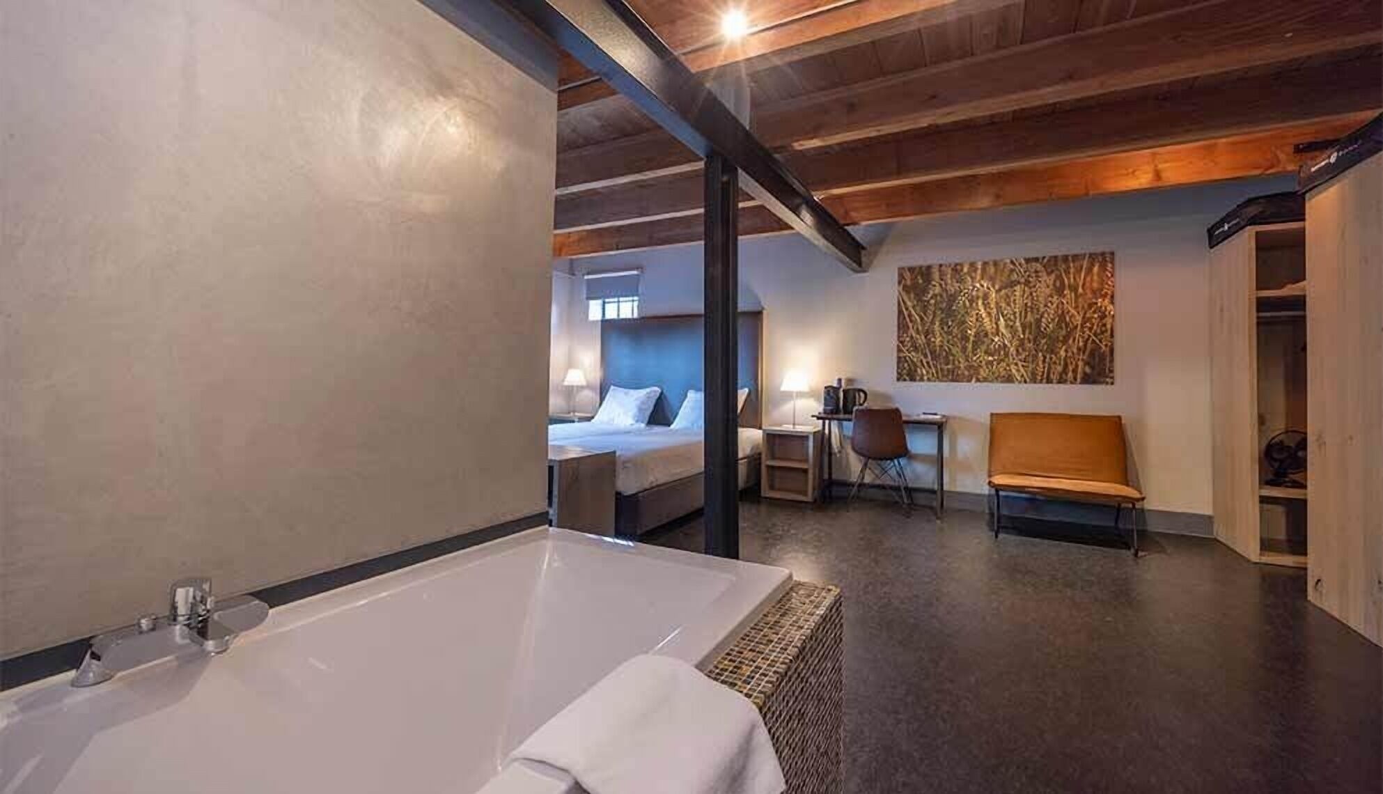 Een moderne hotelkamer met een groot bad, een bed, een bureau en een stoel.