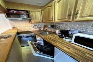 A kitchen with wooden cabinets, a stainless steel sink, a microwave, and a dishwasher. - Stunning Alpine Base near Termal Bath (Mont-Dore)