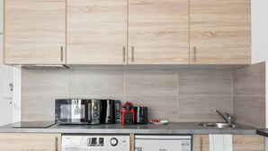 Uma cozinha moderna com armários de madeira, uma pia de aço inoxidável e uma máquina de lavar louça embutida.